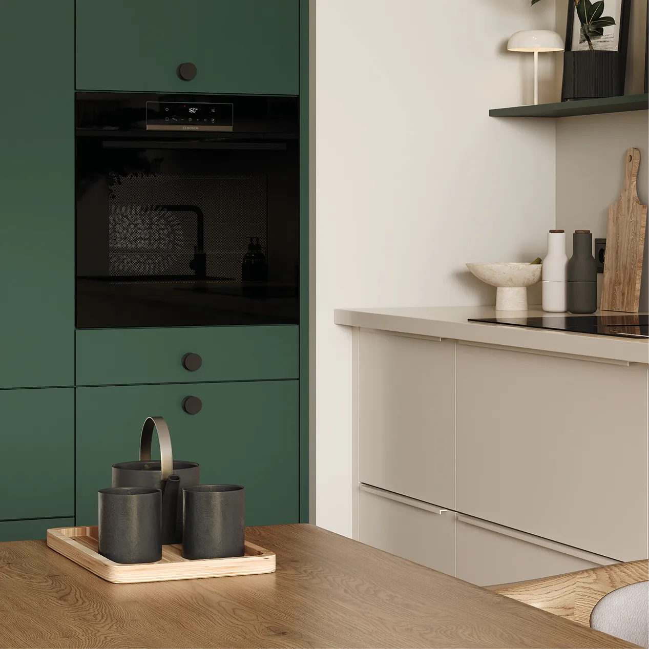 Detail einer modernen Küche mit grünen Hochschränken, schwarzem Einbau Backofen, beigen Unterschränken, Holz Arbeitsplatte und Holztisch mit Tablett und Tassen, skandinavischer Küchenstil.